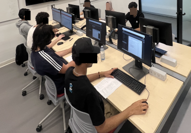 Anonymized students working writing an exam on lab test computers.