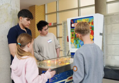 Two children testing a student-modified pinball machine at the YorkU Engineering Open House. 